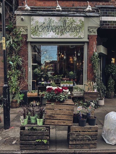 The exterior of Northenflower, a flower shop with a brick facade and a decorative sign above the entrance. The shop window displays lush greenery and floral arrangements inside. Outside, there are woo